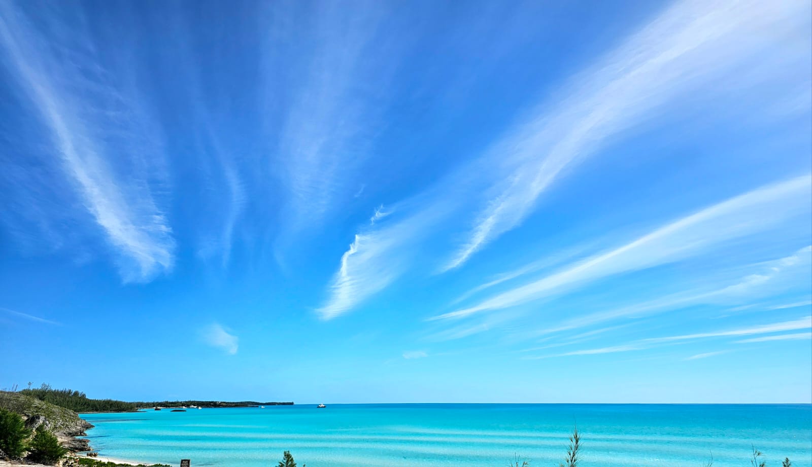 A wide view of vivid turquoise Bahamian water beneath an expansive blue sky